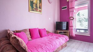 Een slaapkamer met een bed, een televisie en een raam met gordijnen.