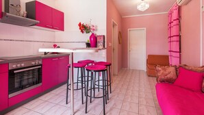 Een keuken met roze kastjes, een fornuis en barstoelen.