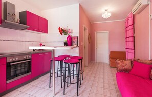 A kitchen with pink cabinets, a stove, and bar stools. - Amazing apartment in Trogir with swimming pool (Trogir)