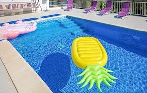 A swimming pool with inflatable toys, a sun lounger, and a tiled deck area. - 3 bedroom amazing apartment in Split (Split)