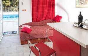 A bedroom with a bed, a red chair, a small table with a bottle and glass, and a view of a pool. - 3 bedroom amazing apartment in Split (Split)
