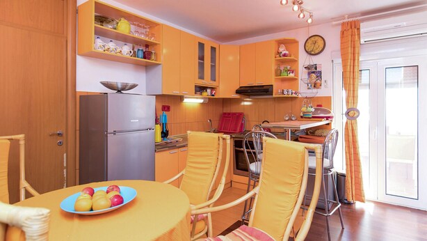 Eine kompakte Küche mit Kühlschrank, Herd und Essbereich mit Stühlen und Tisch.