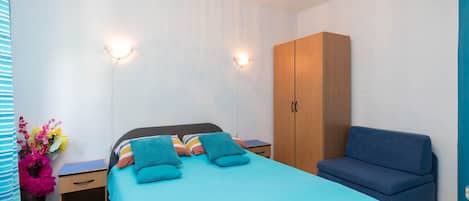A bedroom with a bed, bedside tables, a wardrobe, and a sofa.