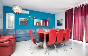 A dining area with a blue wall, a red sofa, and a dining table with red chairs. - Beautiful apartment in Trogir (Trogir)