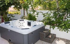 Ein Whirlpool mit Bedienfeld, umgeben von einer weißen Wand und Grünpflanzen.
