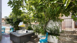A hot tub, a blue chair, and a staircase leading to a covered area with a view of a pool and buildings in the background. - Lovely apartment in Seget Vranjica with WiFi (Seget Vranjica)