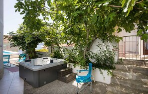 A hot tub, a blue chair, and a staircase leading to a covered area with a view of a pool and buildings in the background. - Lovely apartment in Seget Vranjica with WiFi (Seget Vranjica)
