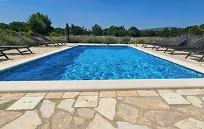 A rectangular swimming pool with a stone border, surrounded by lounge chairs and a clear sky. - Pet friendly home in Ervenik (Ervenik)