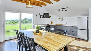A modern kitchen with a wooden dining table, grey cabinets, and a view of the countryside. - Pet friendly home in Ervenik (Ervenik)