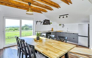 A modern kitchen with a wooden dining table, grey cabinets, and a view of the countryside. - Pet friendly home in Ervenik (Ervenik)