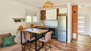 A modern kitchen with a central island, wooden flooring, and a brick accent wall. - Awesome home in Ervenik (Ervenik)