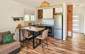 A modern kitchen with a central island, wooden flooring, and a brick accent wall. - Awesome home in Ervenik (Ervenik)