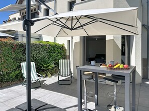 An outdoor patio area with a table, chairs, and a large umbrella. - Les Sylphes by Interhome (Pornic)