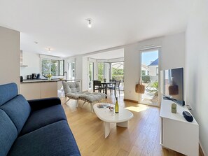 A modern living room with a sofa, a coffee table, and a TV on a stand. - Les Sylphes by Interhome (Pornic)