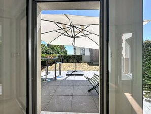 A patio area with a table, chairs, and a large umbrella. - Les Sylphes by Interhome (Pornic)