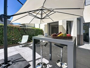 Eine Terrasse im Freien mit Tisch, Stühlen und einer Obstschale.
