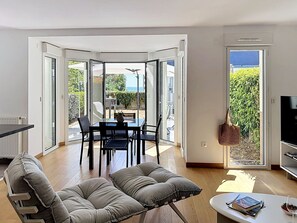 A modern living room with a dining area, a sofa, a coffee table, and a TV. - Les Sylphes by Interhome (Pornic)