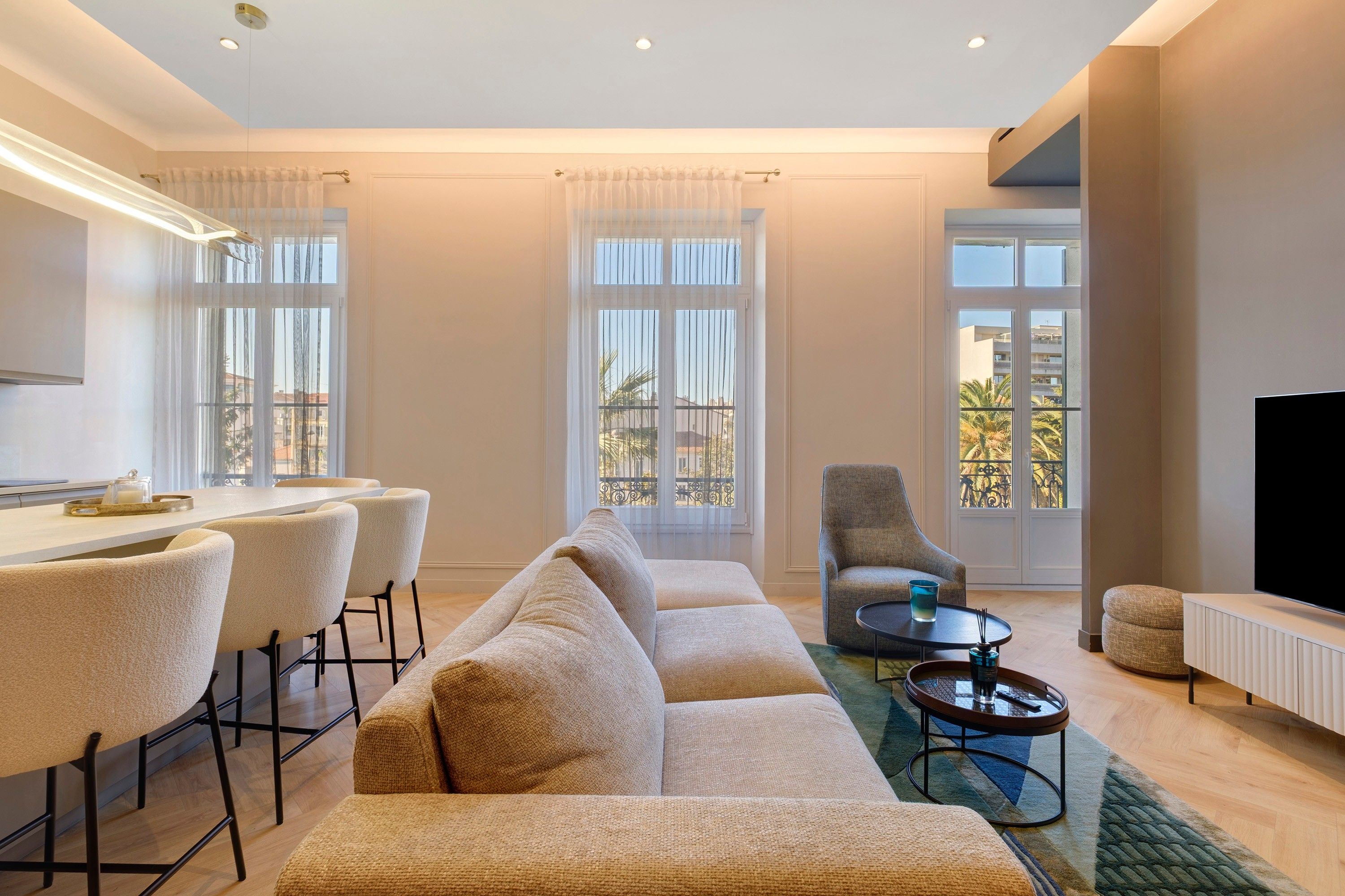Uma sala de estar moderna com sofá, área de jantar com cadeiras, mesa de centro e televisão.