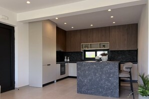 A modern kitchen with a marble island, wooden cabinets, and recessed ceiling lights. - Mirena Exclusive Apartment 1 (Rhodes)