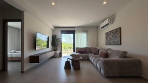 Ein modernes Wohnzimmer mit großem Flachbildfernseher, einem Ecksofa, einem Couchtisch und einer Topfpflanze.