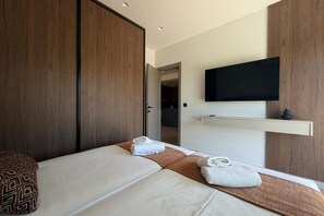 Ein modernes Hotelzimmer mit einem Bett, einem an der Wand befestigten Fernseher und einem Holzschrank.