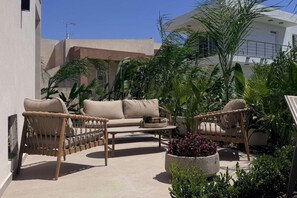 An outdoor seating area with wicker furniture and a potted plant. - Mirena Exclusive Apartment 1 (Rhodes)