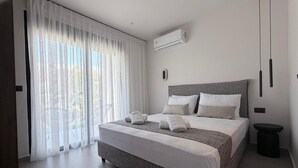 Ein modernes Schlafzimmer mit einem großen Bett, einem kleinen Nachttisch und Blick durch leichte Vorhänge.
