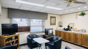 A room with a television, seating area, kitchenette, and a window with blinds. - King Bed |Non-Smoking (Forsyth MT)