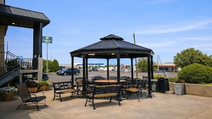 A gazebo with outdoor seating, a Holiday Inn sign, and a parking lot in the background. - 2 Queen Beds Non-Smoking (Forsyth MT)