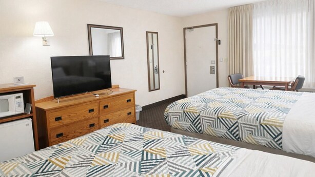 A hotel room with two beds, a TV, a desk, and a mirror. - 2 Queen Beds Non-Smoking (Forsyth MT)