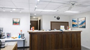 A reception area with a wooden counter, a clock, and artwork on the walls. - 2 Queen Beds Non-Smoking (Forsyth MT)