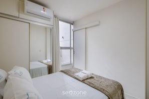 Quarto de hotel com cama, janela e ar condicionado.