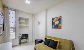 Quarto pequeno e moderno com cama, cadeira, escrivaninha e guarda-roupa.