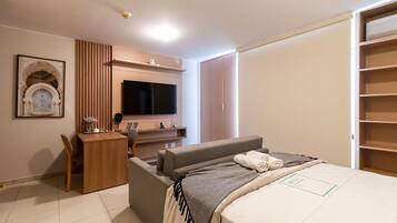 A modern bedroom with a bed, a desk, a chair, a television, and a wardrobe.
