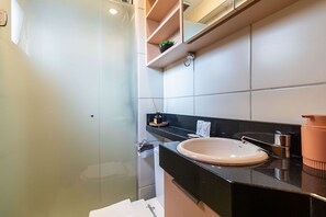 A modern bathroom with a glass shower enclosure, a black countertop, and a white sink. - Full Studio Asa Sul Brasilia - Gdp0107 (Brasília)