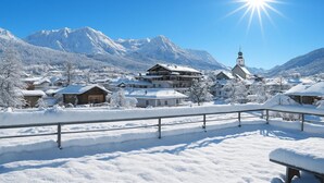 Un pueblo cubierto de nieve con una iglesia destacada y montañas al fondo.