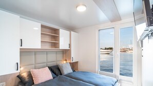 Ein modernes Schlafzimmer mit Bett, Nachttischen, einem Einbauschrank und Meerblick durch eine Glastür.