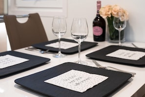 A table set with black placemats, wine glasses, and a bottle of wine.