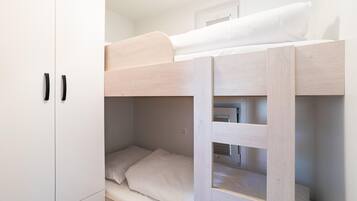 A bunk bed with a white wardrobe beside it.