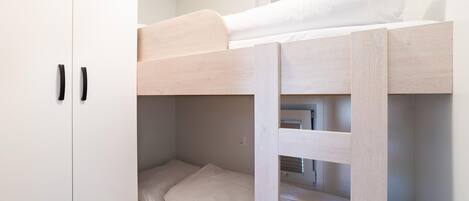 Una cama litera con un armario blanco a su lado.