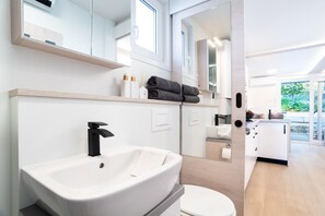 A modern bathroom with a large sink, mirror, and a toilet.