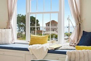 A cozy room with a window seat, a cushion, a book, and a cup. - Waterfront - Sauna -Steps To Beach! (Saco)