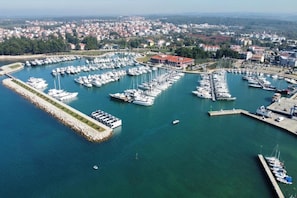 Luftaufnahme einer Marina mit zahlreichen vertäuten Booten, umgeben von einer Küstenstadt.