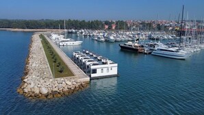 A marina with boats docked, a stone breakwater, and a row of buildings along the water's edge. - Dream houseboat with sea view and hot tub (Novigrad)