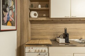 A kitchen with wooden cabinets, a Siemens oven, and a countertop with a cutting board and a coffee machine. - '1 Room - Apartment Basement Floor' with Wi-Fi (Hüfingen)
