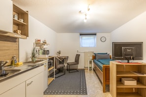 Ein kleines Zimmer mit Küchenzeile, einem Bett, einem Schreibtisch und einer Heizung.