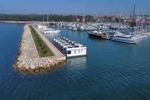 A marina with boats docked, a dockside building, and a rocky breakwater.