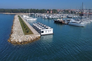 A marina with boats docked, a stone breakwater, and a row of buildings along the water's edge. - Dream houseboat with sea view and hot tub (Novigrad)