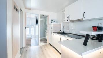 Una cocina moderna con armarios blancos, encimera negra y vistas al exterior a través de una puerta.