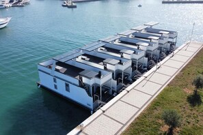 Ein Objekt am Wasser mit einer Reihe verbundener Gebäude, vermutlich Wohn- oder Geschäftseinheiten, und einem Steg, der ins Wasser führt.
